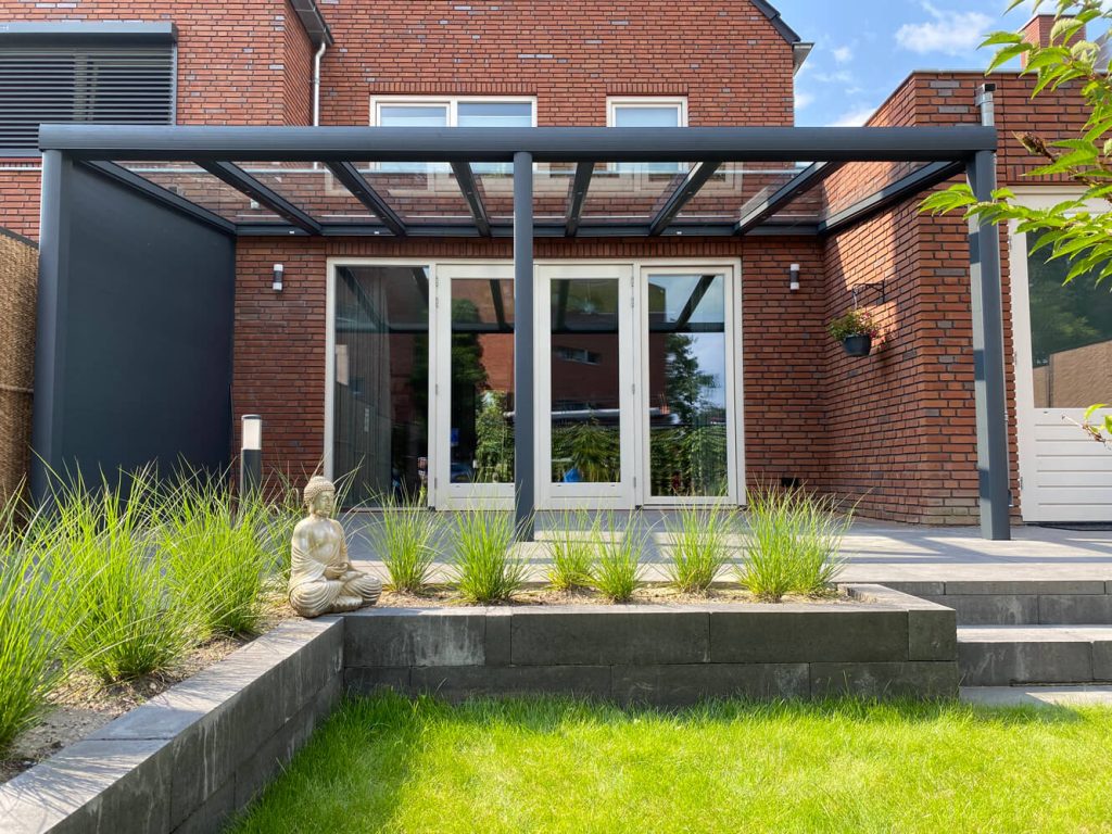 Schlichte Aluminium Terrassenüberdachung mit Glasdach und integriertem Sonnenschutz, teilweise offen für frische Luft.