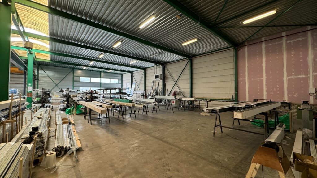 Produktionsbereich von Jolie Patio mit Arbeitstischen und Aluminiumprofilen zur Herstellung von Aluminium Terrassenüberdachungen, im Hintergrund Werkzeuge und Materialien.