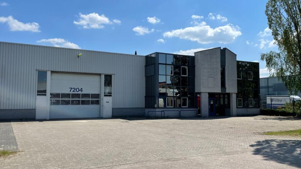Firmengebäude von Jolie Patio mit modernem, klarem Design, großen Fenstern und weißer Fassade auf einem Industriegebiet.